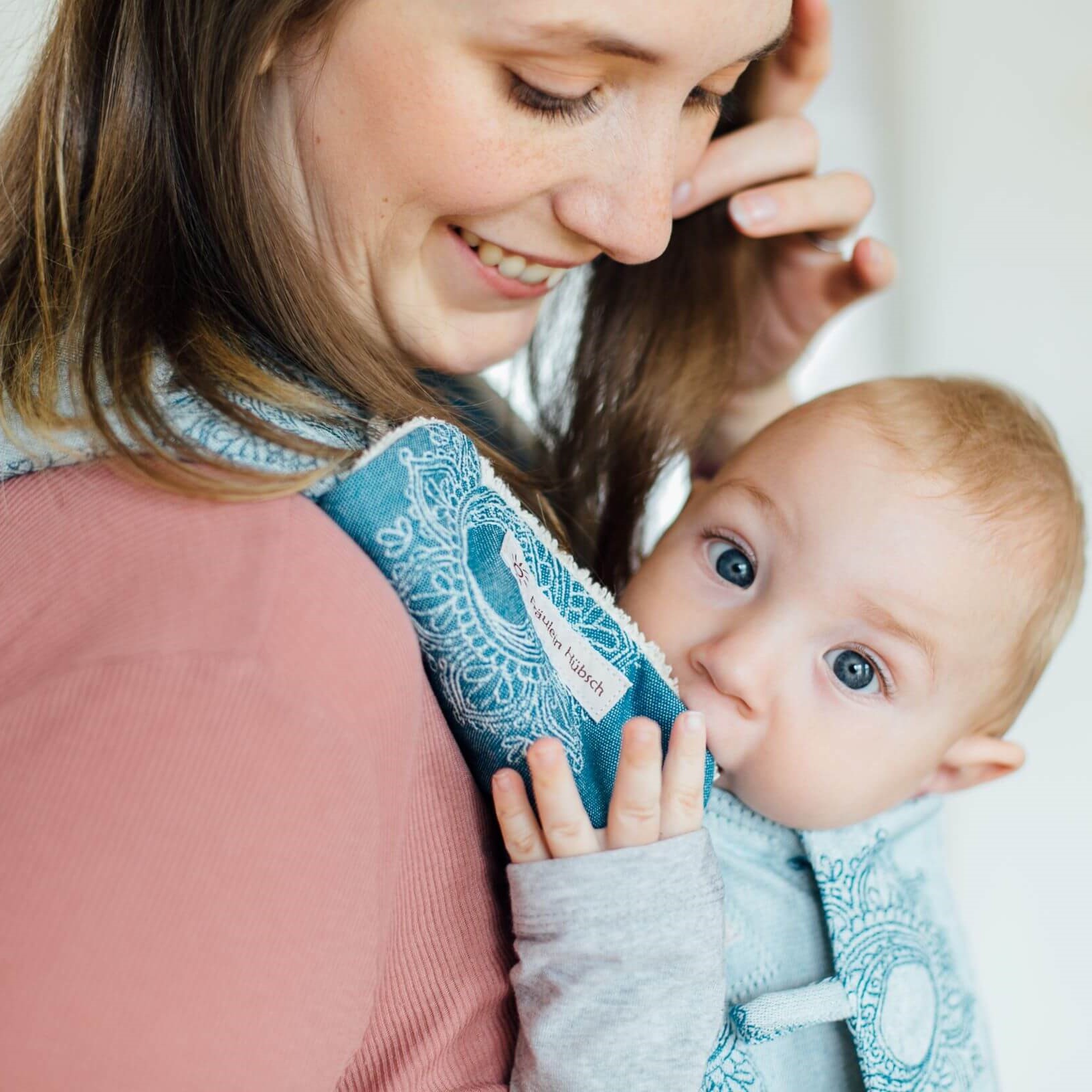 Baby in Trage mit Gurtschonern