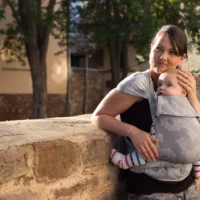 eine Frau trägt Baby mit WrapCon Babytrage vor dem Bauch