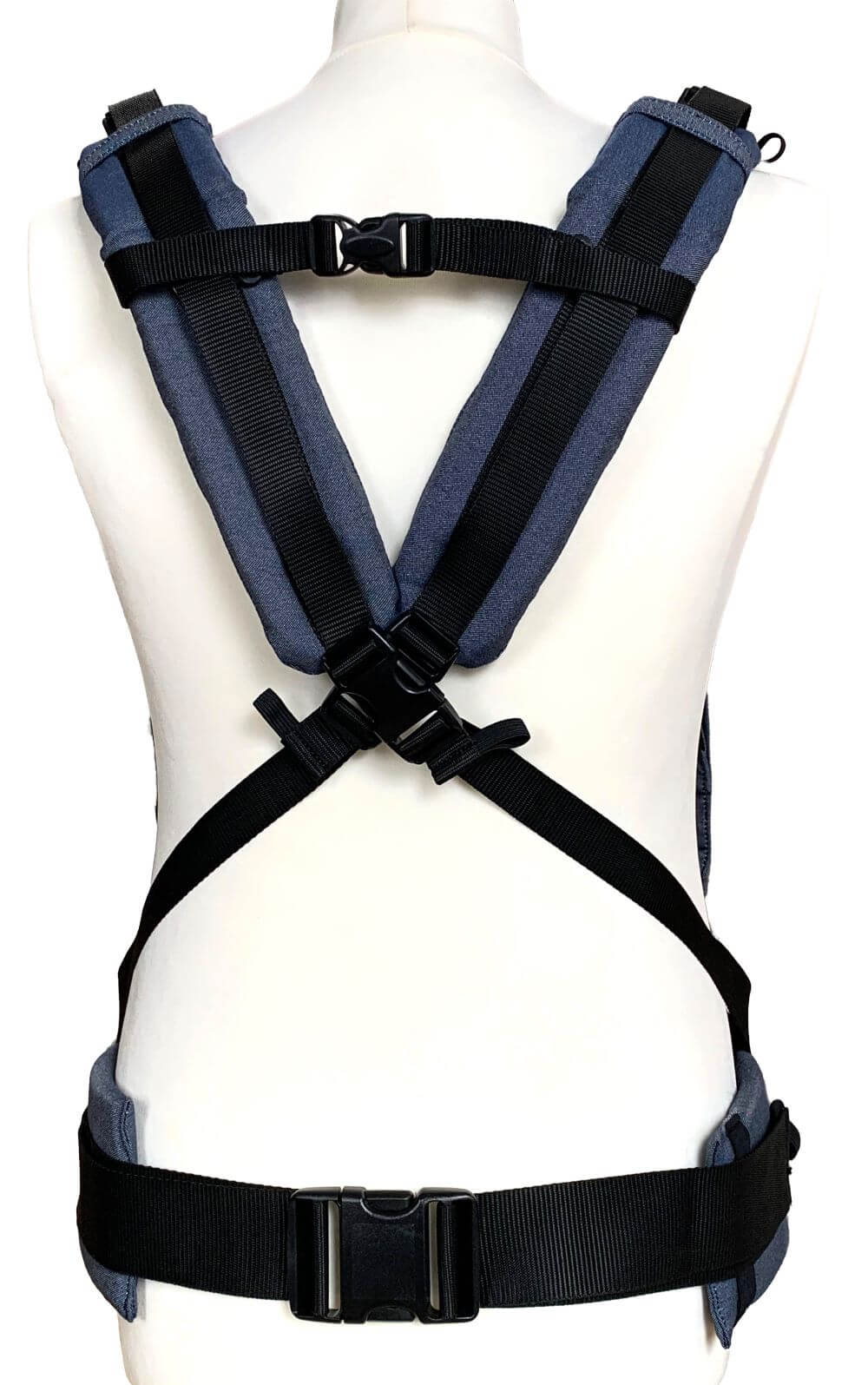 Fullbuckle Onesize Indigo Rueckansicht gekreuzt Rückseite einer Fullbuckle Babytrage in Denimblau auf einer Schneiderpuppe. Die Träger sind überkreuzt.