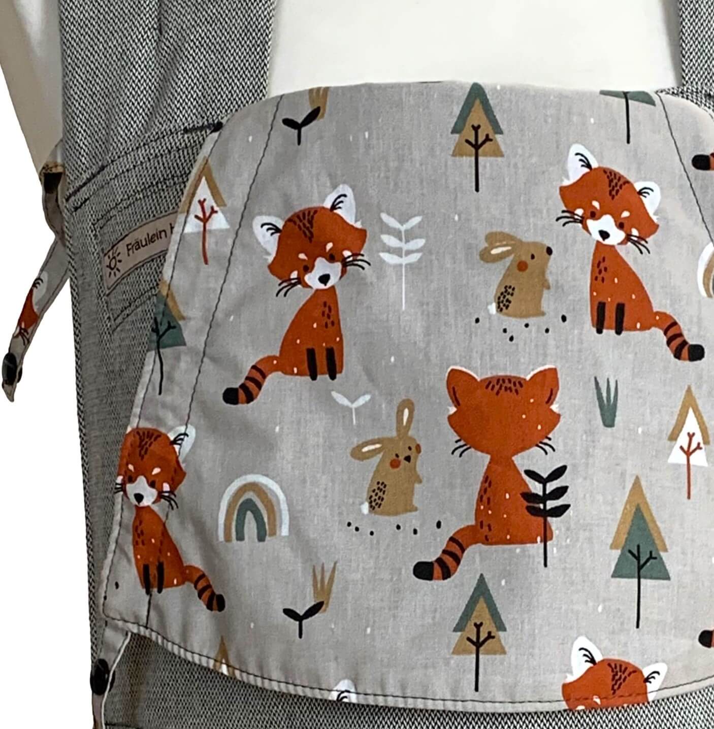 SoftTai V2 Babysize Foxes Detail Detailansicht der Kopfstütze aus Dekostoff. Auf grauem Hintergrund sind orangebraune sitzende Füchse, Bäume und Hasen abgebildet.