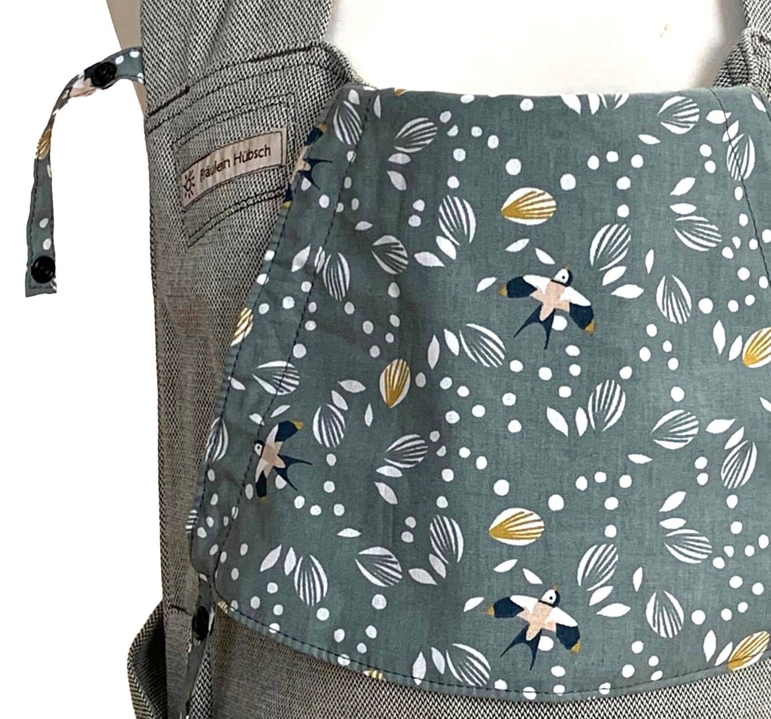 Detailansicht der Kopfstütze: salbeigrüner Hintergrund, auf dem weiße Blätter und Schwalben in Weiß, Schwarz und Ocker zu sehen sind.