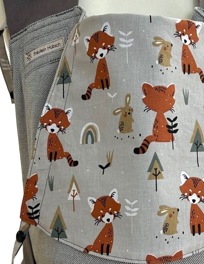 Fräulein Hübsch Mei Tai Babytrage in Hellgrau mit grauen Schulterträgern und Bauchgurt. Die Kopfstütze ist aus grauem Stoff mit Füchsen, Hasen und Regenbogen.