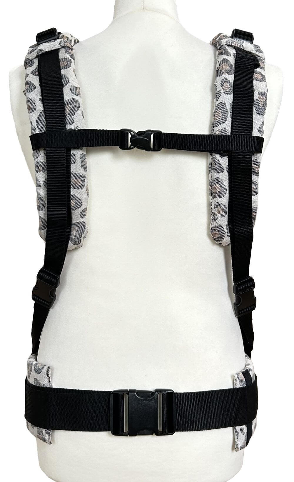 Fullbuckle Onesize Leoprint Ruckansich parallel Fullbuckle Rucksacktrage in der Farbe Leoprint auf einer Schneiderpuppe. Alle Gurt schließen mit SChnallen wie bei einem Rucksack, kein Binden. Ansicht von hinten mit parallelen Trägern.