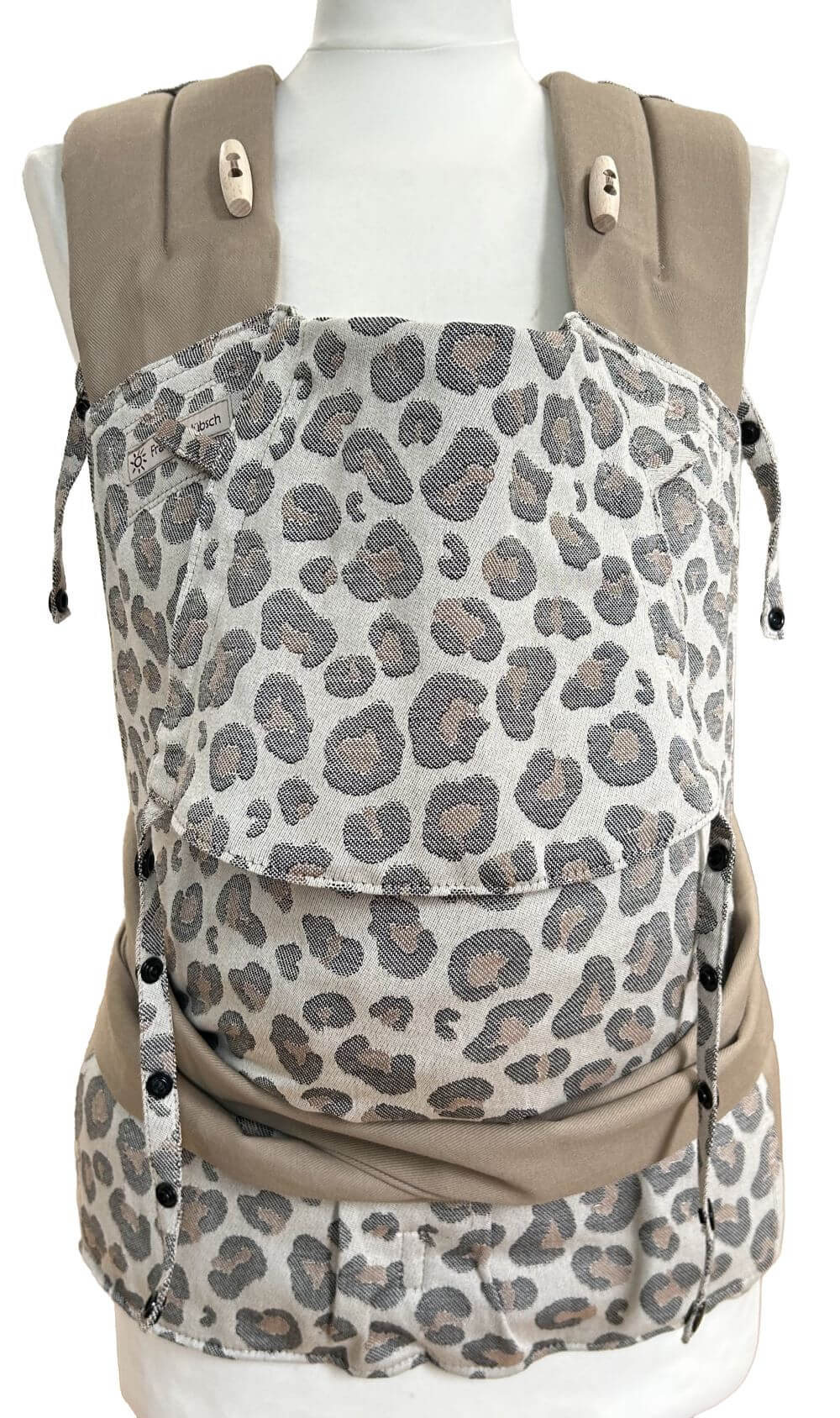 Mei Tai Babysize Leoprint Frontal Babytrage Mei Tai von Fräulein Hübsch in hellem Leoprint in Schwarz und Braun auf einer Schneiderpuppe in frontaler Ansicht. Der Hüftgurt schließt mit Schnalle, die Schulterträger sind zu binden. Die Träger sind aus beigem festen Biobaumwollstoff.