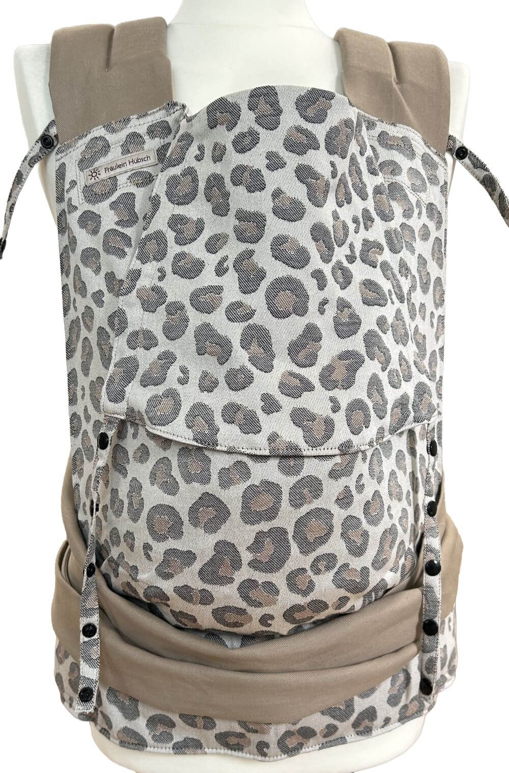 Mei Tai Toddlersize Leoprint Frontal Babytrage Mei Tai von Fräulein Hübsch in hellem Leoprint in Schwarz und Braun auf einer Schneiderpuppe in frontaler Ansicht. Der Hüftgurt schließt mit Schnalle, die Schulterträger sind zu binden. Die Träger sind aus beigem festen Biobaumwollstoff.