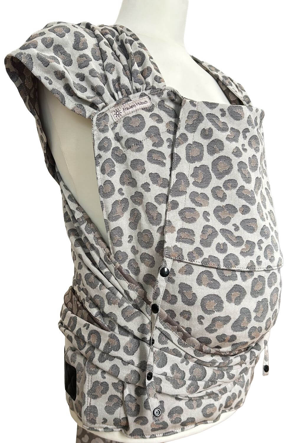 Babytrage WrapCon von Fräulein Hübsch in Leoprint in schwarz und braun auf hellem Grund. Die Träger sind auffächerbar und zum verknoten, der Bauchgurt schließt mit einer Schnalle.