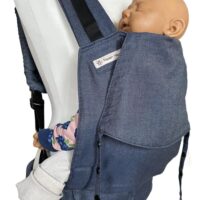 Fullbuckle Rucksacktrage Größe Newborn in der Farbe Denim auf einer Schneiderbüste. In der Trage sitzt eine Puppe. Alle Gurt schließen mit Schnallen wie bei einem Rucksack, kein Binden.