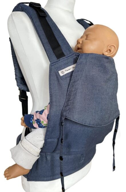 Fullbuckle Rucksacktrage Größe Newborn in der Farbe Denim auf einer Schneiderbüste. In der Trage sitzt eine Puppe. Alle Gurt schließen mit Schnallen wie bei einem Rucksack, kein Binden.