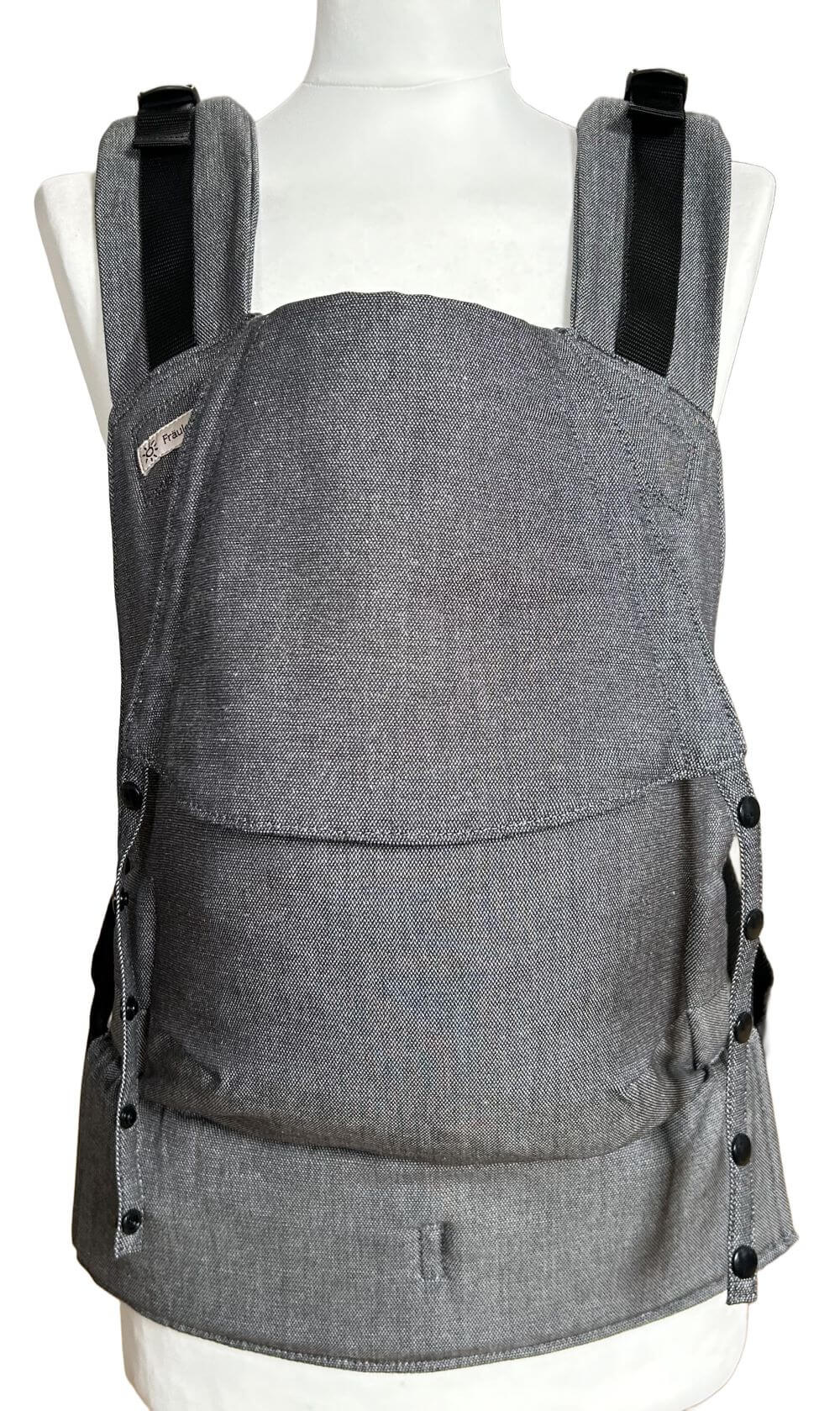 Fullbuckle Newborn Graphite Frontal Fullbuckle Rucksacktrage Größe Newborn in der Farbe Graphite auf einer Schneiderbüste. Alle Gurte schließen mit SChnallen wie bei einem Rucksack, kein Binden.