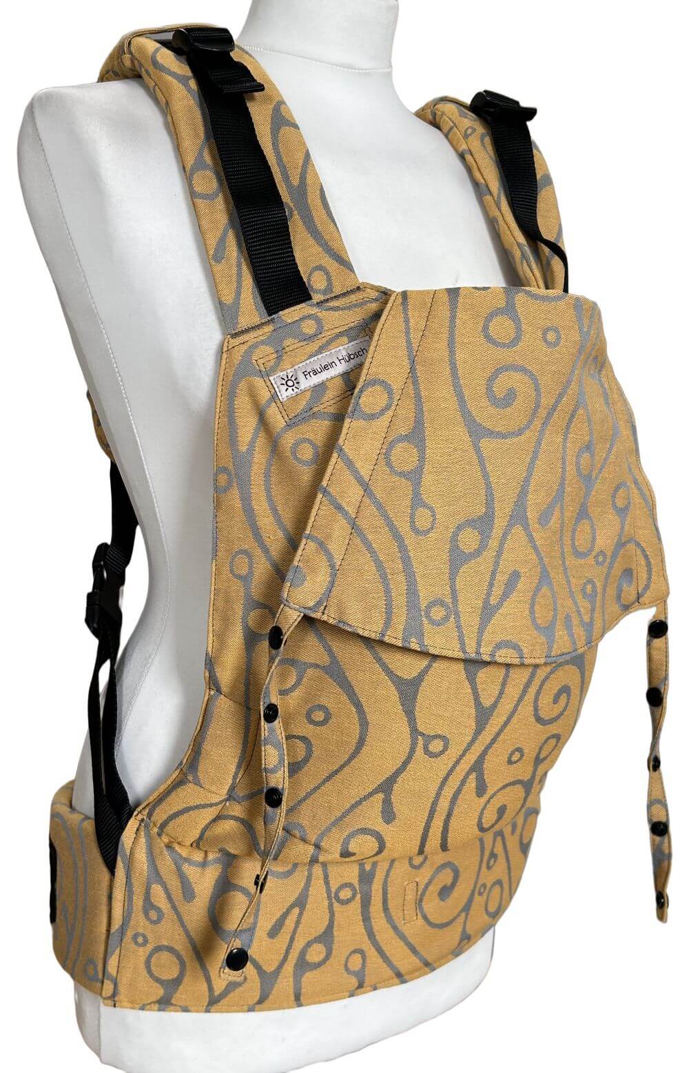 Fullbuckle Newborn Seaweed Bernstein seitlich Fullbuckle Rucksacktrage Größe Newborn mit grauem Muster auf gelbem Grund auf einer Schneiderbüste. Alle Gurte schließen mit Schnallen wie bei einem Rucksack, kein Binden.