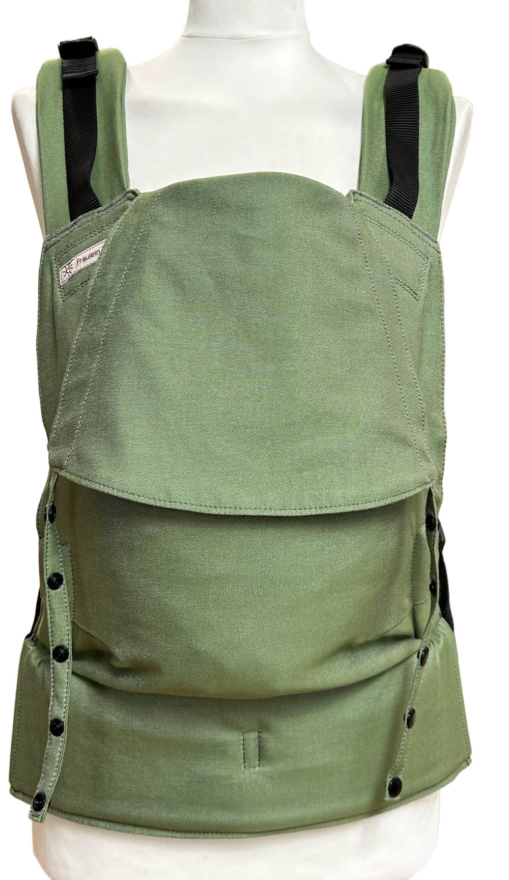 Fullbuckle Rucksacktrage Größe Newborn in der Farbe Kale auf einer Schneiderbüste. Alle Gurte schließen mit Schnallen wie bei einem Rucksack, kein Binden.