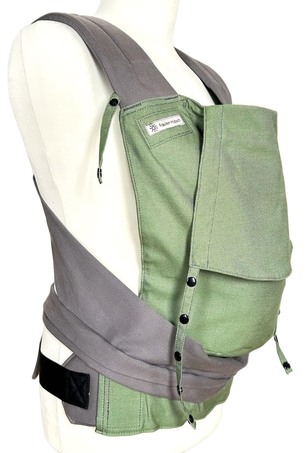 Mei Tai Toddlersize Kale seitlich Fräulein Hübsch Mei Tai Toddlersize in einem schönen Dunkelgrün auf einer Schneiderpuppe ausgestellt. Die Träger sind grau und aus festem Baumwollstoff.