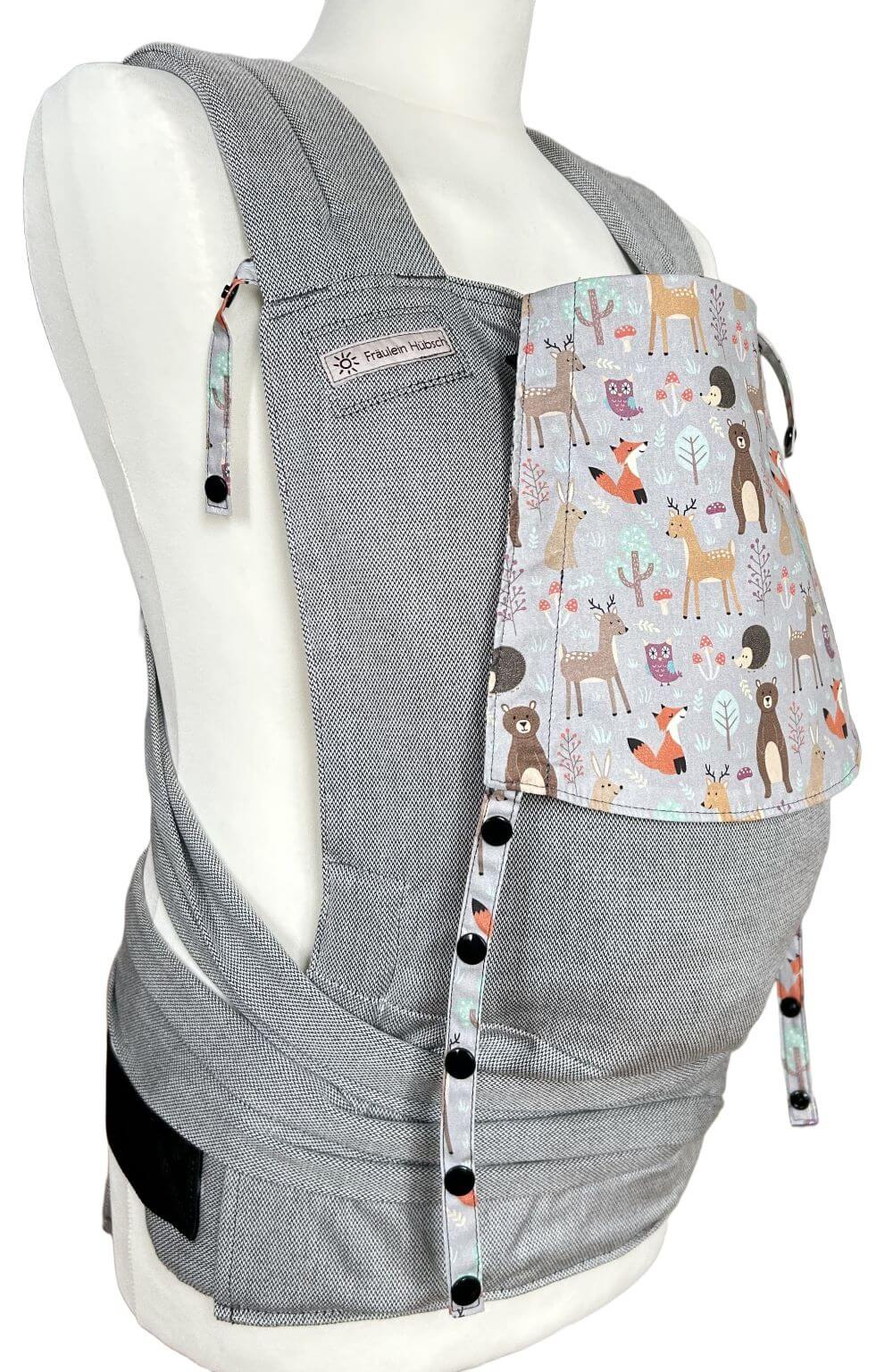 SoftTai V2 Toddlersize Magic Forest seitlich Fräulein Hübsch SoftTai Toddlersize in Hellgrau mit bunter Kopfstütze, auf der bunte Waldtiere auf hellgrauem Grund abgebildet sind. Die Trage wird auf einer Schneiderpuppe gezeigt.