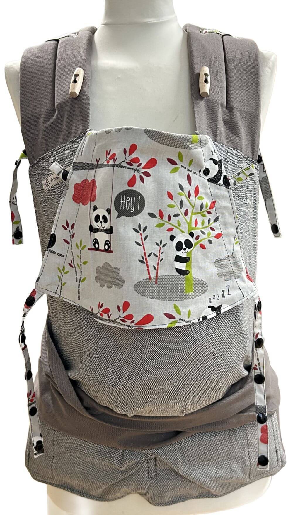 Mei Tai Babysize Panda frontal Fräulein Hübsch Mei Tai Babysize in Hellgrau mit bunter Kopfstütze im Pandabären-Design auf hellgrauem Hintergrund, präsentiert auf einer Schneiderpuppe.