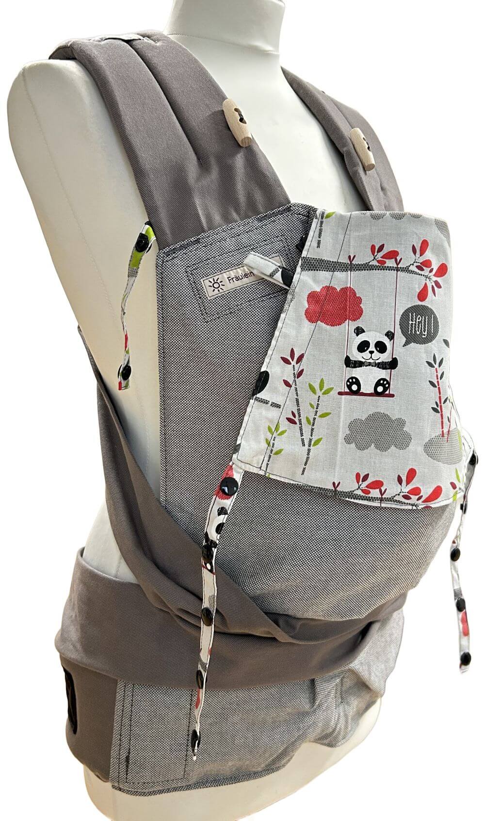 Mei Tai Babysize Panda seitlich Fräulein Hübsch Mei Tai Babysize in Hellgrau mit bunter Kopfstütze im Pandabären-Design auf hellgrauem Hintergrund, präsentiert auf einer Schneiderpuppe.