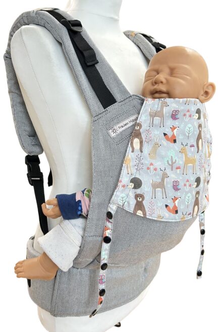 Fräulein Hübsch Fullbuckle Newborn in Hellgrau mit bunter Kopfstütze, auf der bunte Waldtiere auf hellgrauem Grund abgebildet sind. Die Trage wird auf einer Schneiderpuppe gezeigt.