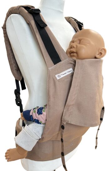 Fullbuckle Rucksacktrage Größe Newborn in der Farbe Toffee auf einer Schneiderbüste. In der Trage sitzt eine Puppe. Alle Gurte schließen mit Schnallen wie bei einem Rucksack, kein Binden.