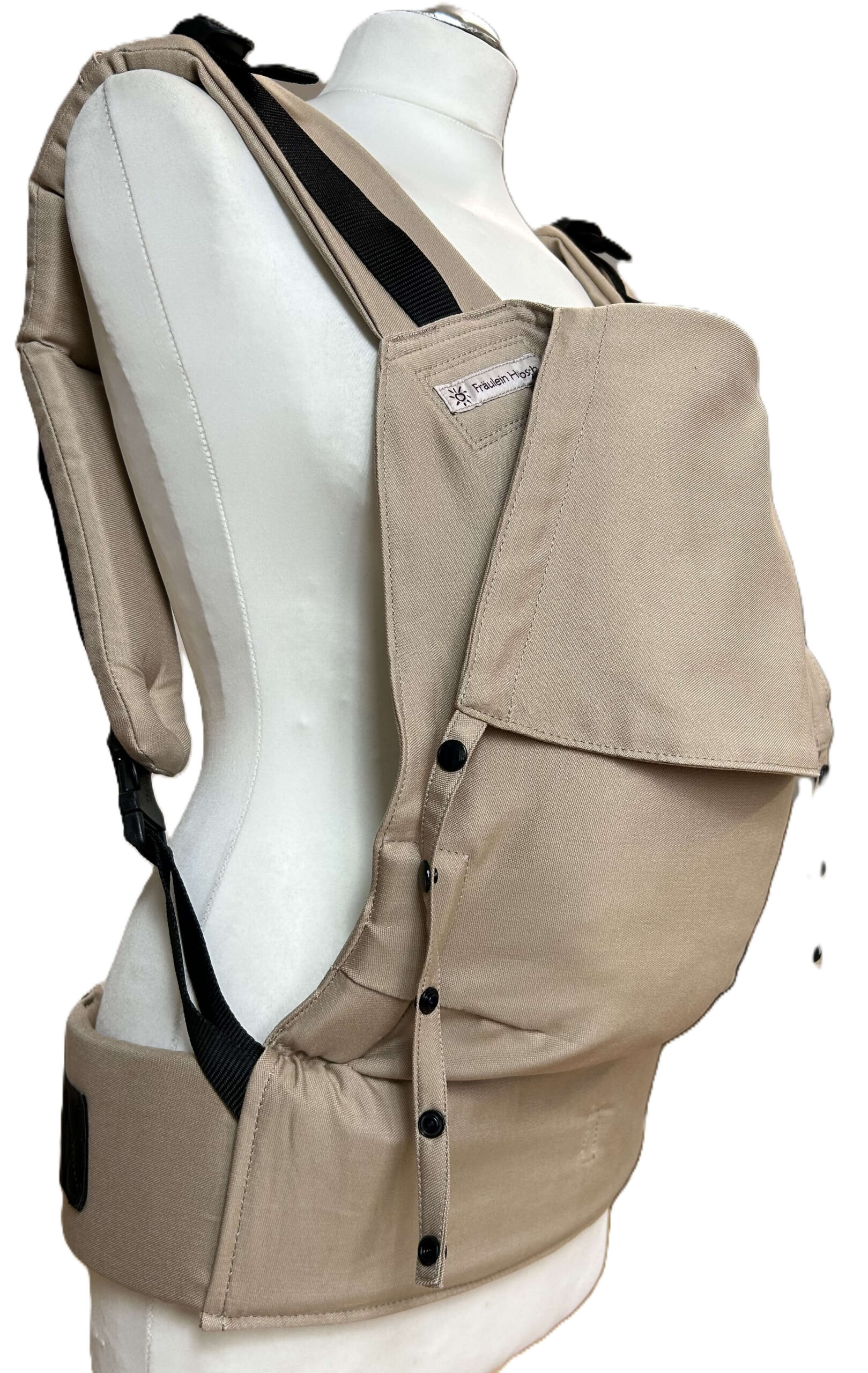 Fullbuckle Newborn Light Taupe seitlich Fullbuckle Rucksacktrage Größe Newborn in der Farbe Light Taupe auf einer Schneiderbüste. In der Trage sitzt eine Puppe. Alle Gurt schließen mit Schnallen wie bei einem Rucksack, kein Binden