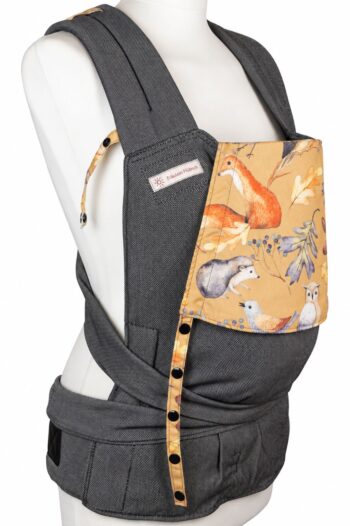 Fräulein Hübsch SoftTai Babysize in Dunkelgrau mit bunter Kopfstütze, auf der bunte Waldtiere wie Fuchs, Igel und Eule auf senfgelbem Grund abgebildet sind. Die Trage wird auf einer Schneiderpuppe gezeigt.